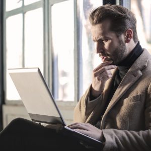 Confused man looking at laptop