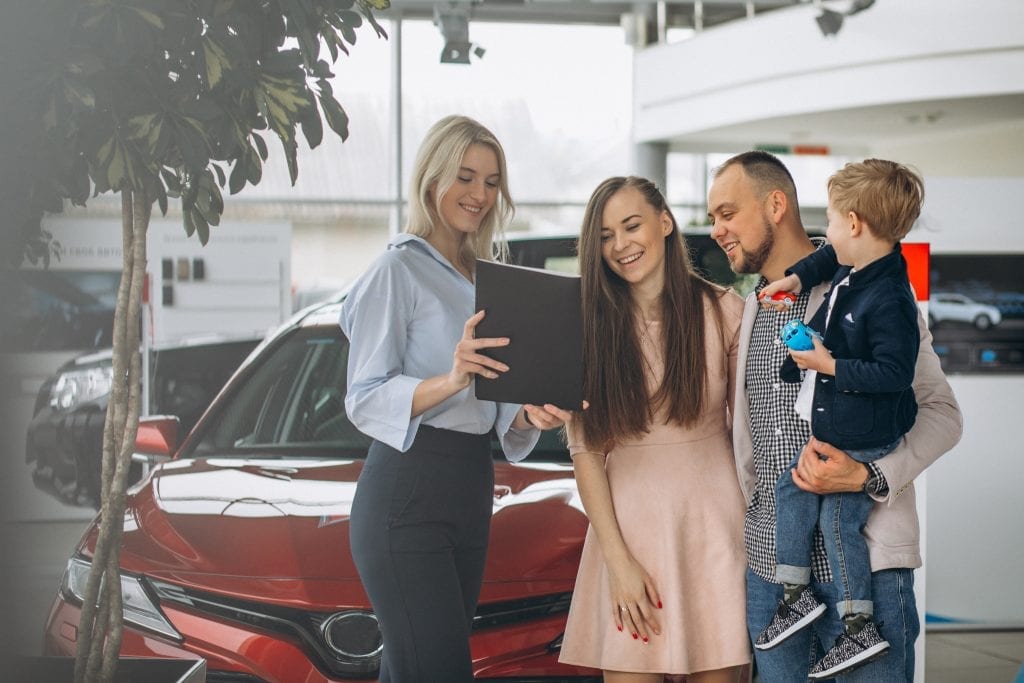 Family with son choosing a car in a car showroom