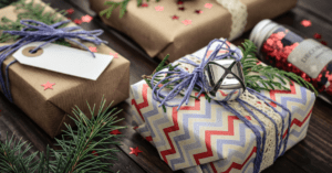 woodsy looking presents in festive gift wrap with fresh greenery surrounding them