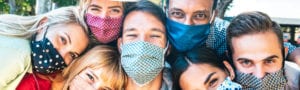 group of diverse friends leaning on one another wearing masks