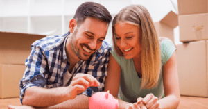 young couple putting money into a piggy bank
