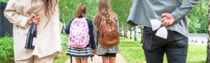 parents with champagne behind their backs walking kids back to school