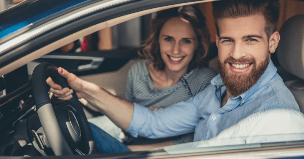 smiling couple looking out of a car buying a car vs leasing