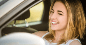 young woman smiling driving a car