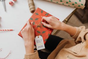 person wrapping a gift with festive paper and gift tag