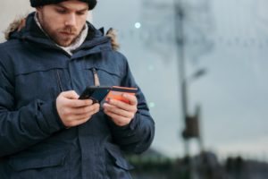 person in snow looking at phone with credit card