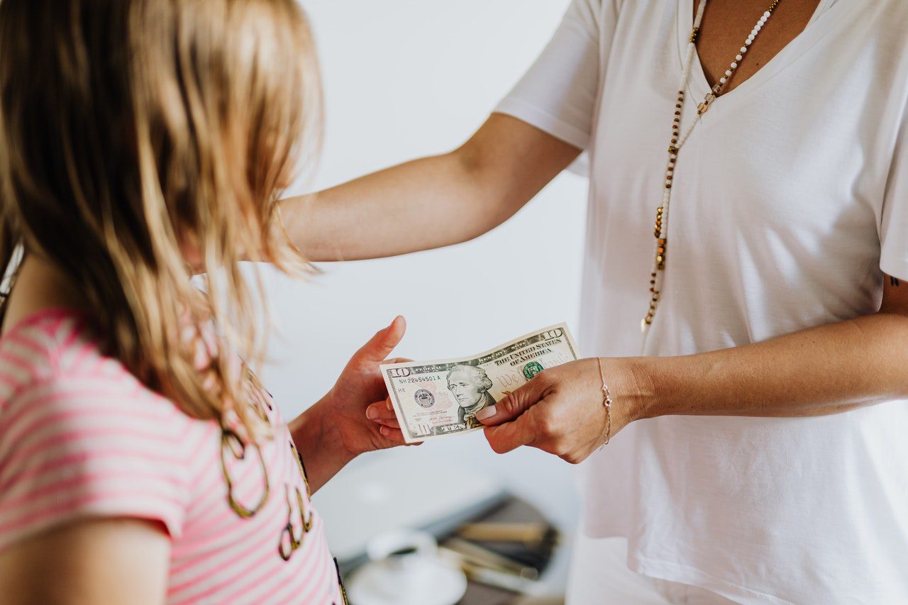 girl in pink shirt getting ten dollars from her mom