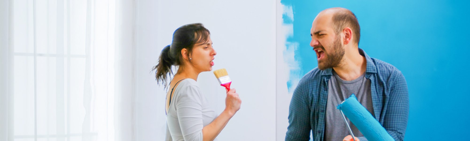woman in front of white wall man in front of blue wall painting