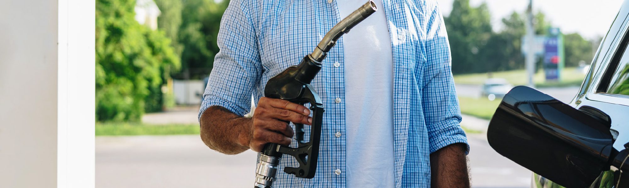 person holding gas nozzle at tank