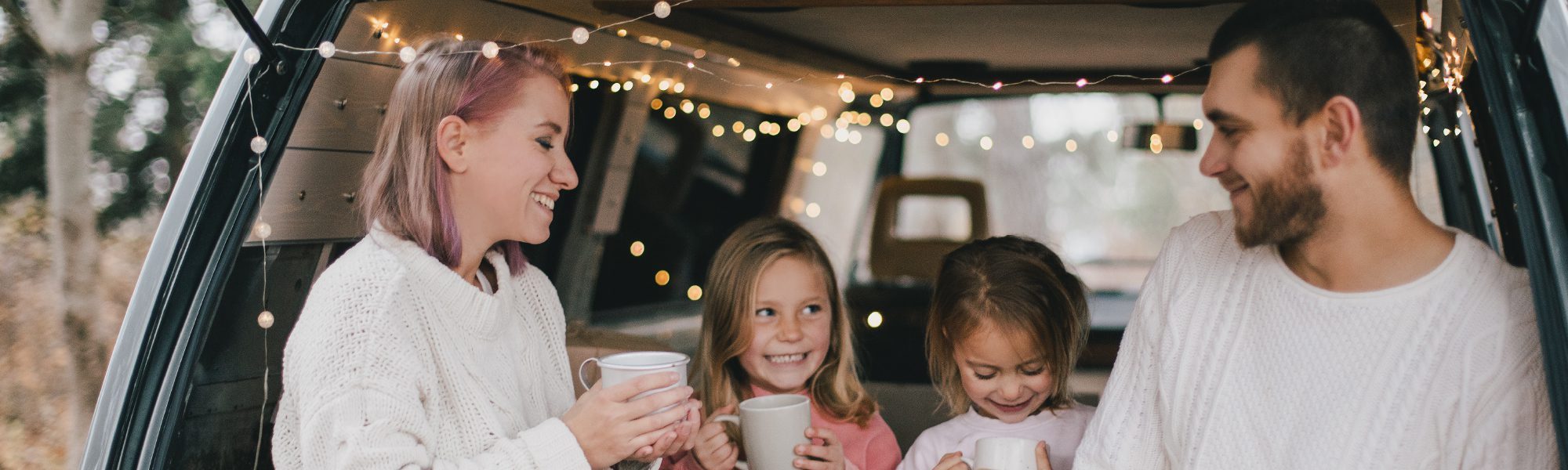 family in the back of a car with mugs and lights