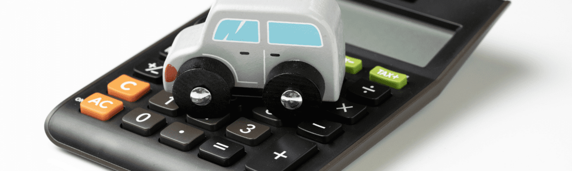 small white toy car sitting on a black calculator