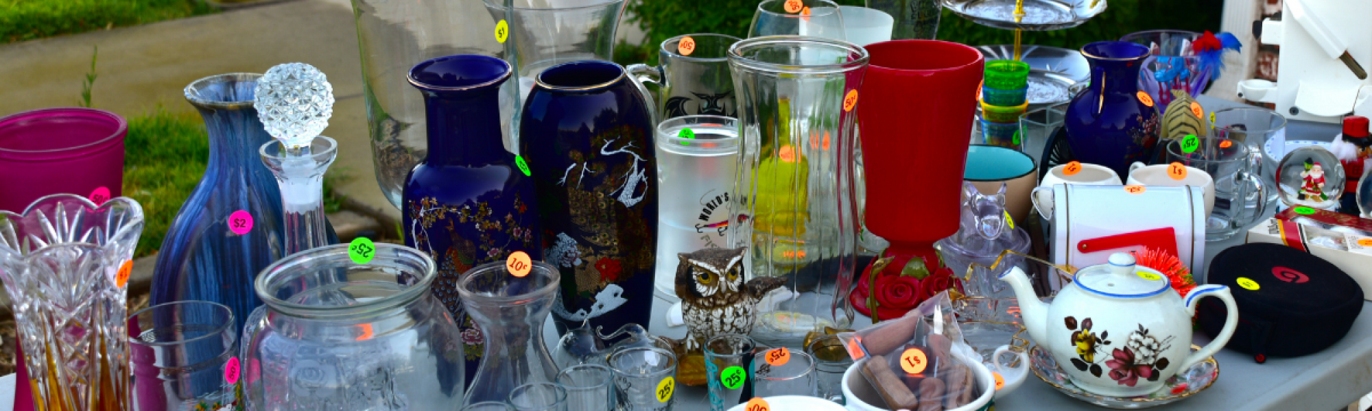 vases and glassware on a table with price stickers at a yard sale