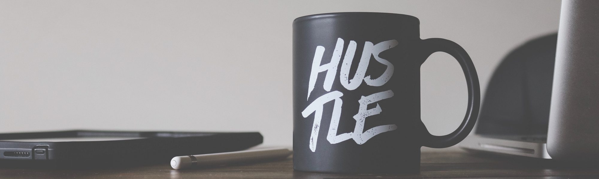 black and white Hustle-printed ceramic mug on table